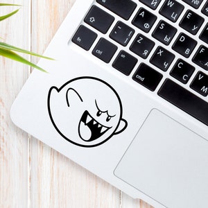 Silver laptop sitting on wood desk with plant