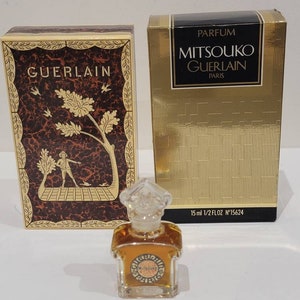 Könnte beinhalten: Eine goldene und schwarze Schachtel mit dem Text "PARFUM MITSOUKO GUERLAIN PARIS" und "15 ml 1/2 FL OZ N°15624". Eine kleinere Schachtel mit dem Text "GUERLAIN" und einem goldenen und braunen Design. Eine kleine durchsichtige Glasflasche mit einem goldenen Verschluss und dem Text "MITSOUKO" in einem Kreis.