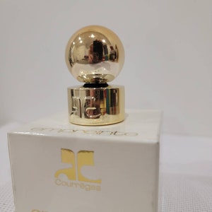 May include: A small bottle of Courr&egrave;ges Empreinte perfume. The bottle is clear glass with a gold cap and a gold ball on top. The box is white with gold lettering. The bottle contains 1/4 fl oz (7 ml) of perfume.