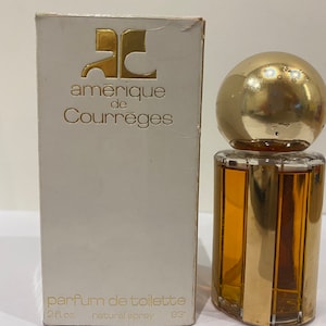 May include: A white box with gold lettering that reads "amerique de Courr&egrave;ges" and "parfum de toilette 2 fl. oz. natural spray 83&deg;". The box is next to a clear glass bottle of perfume with a gold cap and a gold band around the bottle.