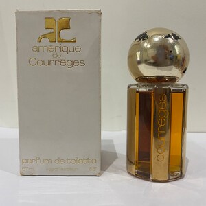 May include: A white box with gold lettering that reads "amerique de Courreges" and "parfum de toilette 57ml vaporisateur 83'" with a clear glass bottle of perfume with a gold cap and a gold label that reads "Courreges".