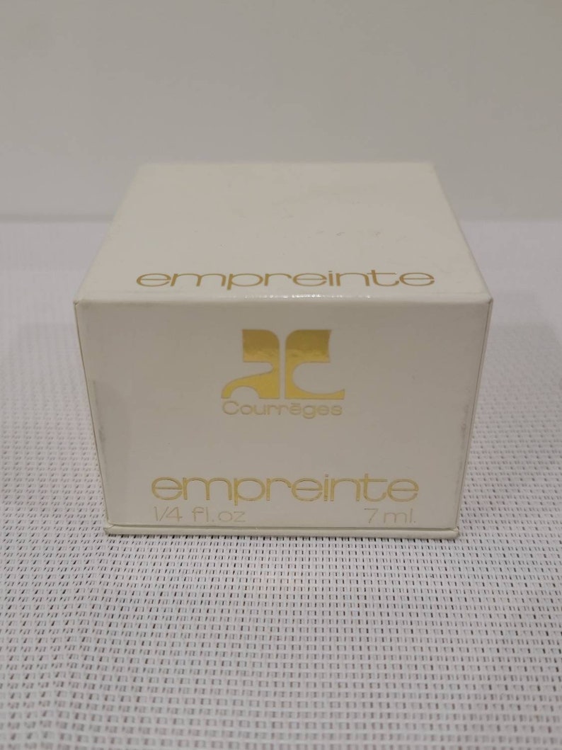 May include: A white box with gold lettering. The box contains a bottle of Courr&egrave;ges Empreinte perfume. The box reads "empreinte" and "Courr&egrave;ges" in gold lettering. The box also reads "empreinte" and "1/4 fl. oz. 7 ml."