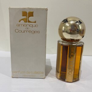 May include: A white box with gold lettering that reads "amerique de Courreges" and "parfum de toilette 57ml vaporisateur 83". A clear glass bottle with a gold cap and gold lettering that reads "Courreges" is in front of the box.