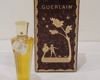 May include: A small bottle of Guerlain Mitsouko perfume in a brown box with gold accents. The box features a stylized illustration of a tree and a person.