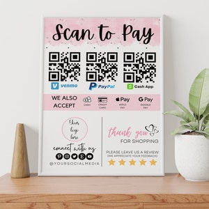 May include: A pink and white sign with the text "Scan to Pay" and QR codes for Venmo, PayPal, and Cash App. The sign also includes icons for cash, credit card, Apple Pay, and Google Pay. The text "We Also Accept" is above the icons. The sign also includes the text "Your logo here", "Connect with us", and "Thank you for shopping". There are five stars below the text "Thank you for shopping".