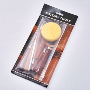 Peut inclure: Un ensemble d'outils de poterie dans un sac en plastique transparent sur un fond noir et blanc. Les outils comprennent une &eacute;ponge, un manche en bois avec une boucle en m&eacute;tal et plusieurs outils &agrave; manche en bois avec des pointes en m&eacute;tal. Le sac porte l'inscription "POTTERY TOOLS".