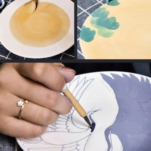 Puede incluir: Un plato de cer&aacute;mica blanco est&aacute; siendo pintado con un pincel. El plato est&aacute; siendo pintado con un esmalte marr&oacute;n claro. El plato est&aacute; sobre una superficie a cuadros.