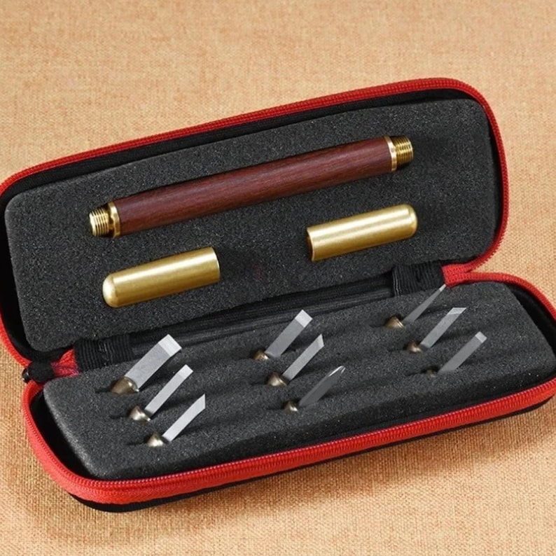 May include: A red carrying case with a zipper closure holds a set of 8 small carving tools with wooden handles and a larger carving tool with a wooden handle and a brass cap. The tools are arranged in a foam-lined case.