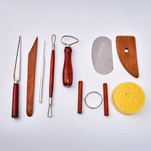 Peut inclure: Un ensemble de 10 outils de poterie pour sculpter et fa&ccedil;onner l'argile. L'ensemble comprend une vari&eacute;t&eacute; d'outils, notamment une palette en bois, un grattoir en m&eacute;tal, une boucle de fil, une &eacute;ponge et plusieurs outils de sculpture avec des manches en bois.