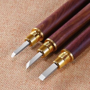 May include: Three wood-handled tools with metal tips. The handles are a dark reddish-brown wood with a wood grain pattern. The metal tips are silver and have a sharp point.