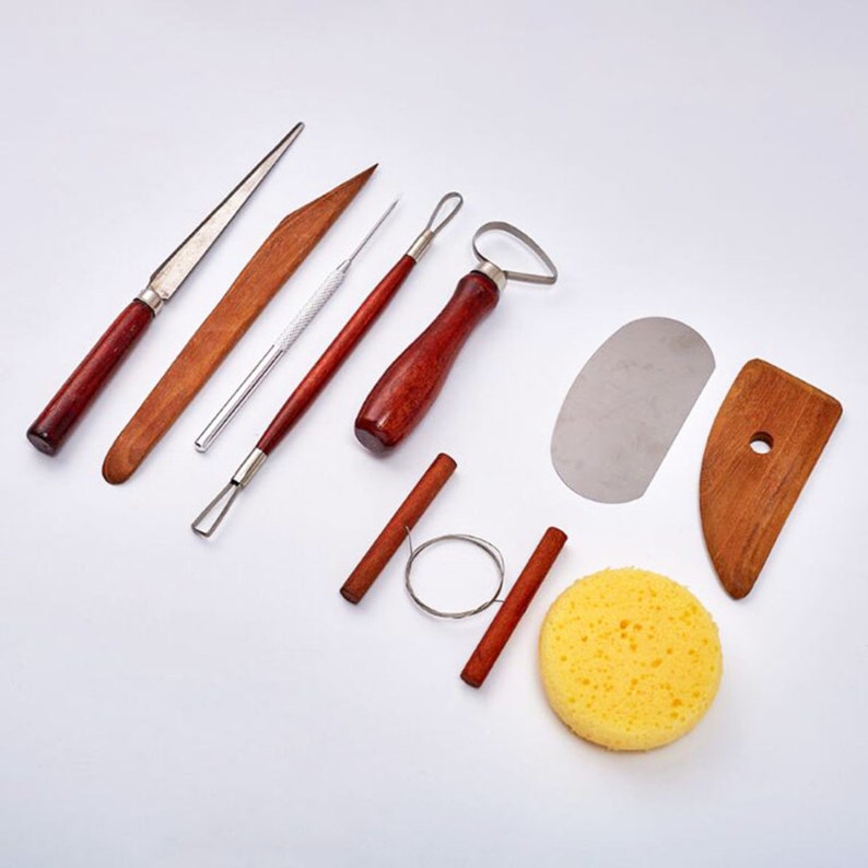 Peut inclure: Un ensemble d'outils de poterie pour sculpter et fa&ccedil;onner l'argile. L'ensemble comprend une vari&eacute;t&eacute; d'outils, notamment une palette en bois, un grattoir en m&eacute;tal, un outil en boucle de fil, une &eacute;ponge et un ensemble d'outils en bois avec des embouts m&eacute;talliques.