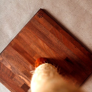 May include: A wooden base with a paw print design for a cat scratching post. The base is made of dark wood with a natural grain pattern.