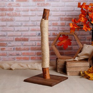 May include: A natural wood cat scratching post wrapped in sisal rope. The post is mounted on a square wooden base.