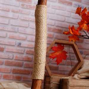May include: A wooden cat scratching post with a natural rope covering. The post is on a wooden base and has a natural wood finish.