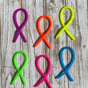 May include: Six colorful, bendable, plastic toys shaped like the infinity symbol. The toys are in the colors purple, orange, yellow, green, pink, and blue.