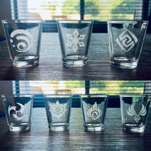 May include: Eight clear glass shot glasses with different etched designs. The designs are white and include a swirl, snowflake, square, crescent moon, heart, flame, and a bird with wings.