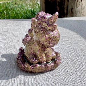 Pu&ograve; includere: Statuetta di unicorno dorata e glitterata con accenti di glitter viola. L'unicorno &egrave; seduto su una base decorativa e ha un singolo corno. &Egrave; un oggetto decorativo stravagante.