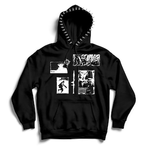 May include: A black hooded sweatshirt featuring a row of silver spikes along the hood edge. The front displays four white graphic panels depicting a mushroom cloud, a running figure, abstract textures, and a rocket launcher, with a central vertical rocket.