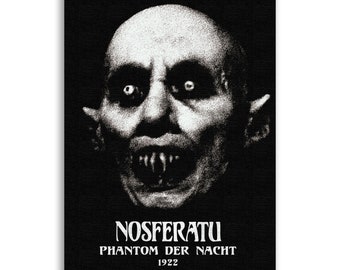 May include: Black and white poster featuring a close-up of Count Orlok, the vampire from the 1922 German Expressionist horror film "Nosferatu: A Symphony of Horror". The poster includes the title "Nosferatu" and the subtitle "Phantom Der Nacht" with the year 1922.