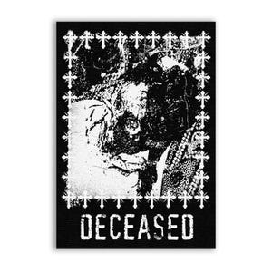 May include: A rectangular black and white graphic print featuring a central distressed image of a skull surrounded by a border of small white crosses. The word DECEASED is printed in a bold, distressed white font at the bottom of the artwork.