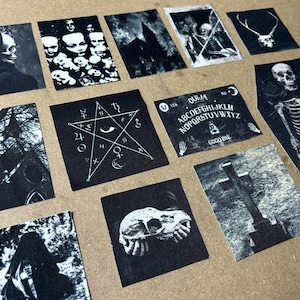 May include: A set of 10 black and white iron-on patches with various gothic and occult themes. The patches feature images of a pentagram, a skull, a Ouija board, a graveyard, and a church.