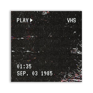 Pode incluir: Uma fita VHS preto e branco com um botão de reprodução e o texto "PLAY" e "VHS". A data "SEP. 03 1985" e a hora "01:35" são exibidas na fita.