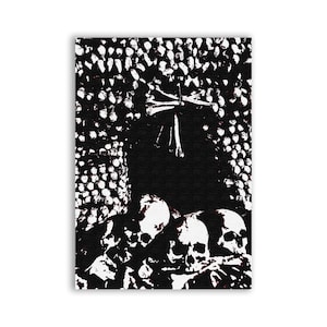 May include: Black and white art print featuring a macabre scene of skulls and bones. The artwork has a high-contrast, graphic style, with a dark background and white highlights. The skulls are clustered together, creating a haunting visual.