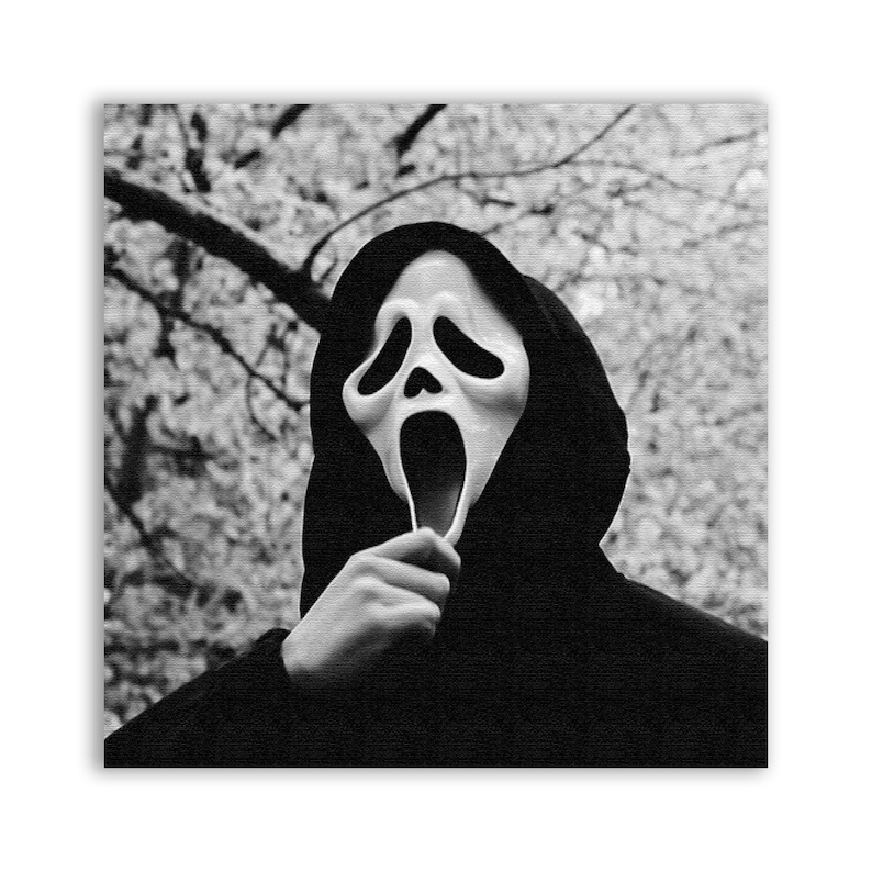 K&ouml;nnte beinhalten: Eine Person tr&auml;gt einen schwarzen Kapuzenpullover und eine wei&szlig;e Plastik-Geistermaske mit weit offenem Mund und gro&szlig;en Augen. Die Maske wird mit einer Hand vor das Gesicht der Person gehalten.