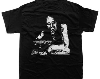 May include: Black t-shirt featuring a black and white graphic of a pale, gaunt figure with a menacing expression. The figure is seated, with the text "CEMETERYCRYPT" in a gothic font below the image. A dark, horror-themed design.