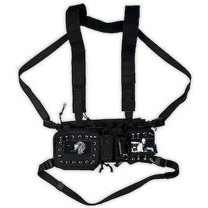 May include: Black tactical chest rig with multiple pockets and adjustable straps. Features metal eyelets and patches with graphic designs. Includes a key ring and various buckles for secure wear.