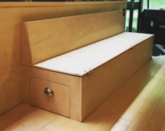 May include: A light wood bench with a hinged lid that opens to reveal storage space. The bench has a simple design and is made of natural wood.