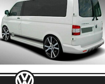 May include: White Volkswagen Transporter van with black racing stripes along the side. The van has tinted windows and custom black and silver alloy wheels. The Volkswagen logo is visible on the side of the van.