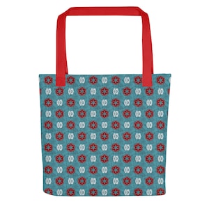 May include: A blue tote bag featuring a repeating pattern of red and white starburst shapes. It has red handles and a matching red strap. The bag is designed for carrying items.