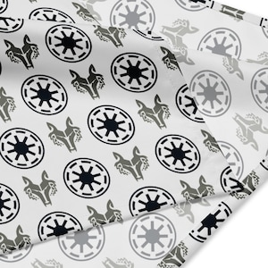 Puede incluir: Tela blanca con un patrón repetido de siluetas de cabeza de lobo negras y grises y diseños circulares de estrellas. La tela está doblada, mostrando el patrón en diferentes ángulos.