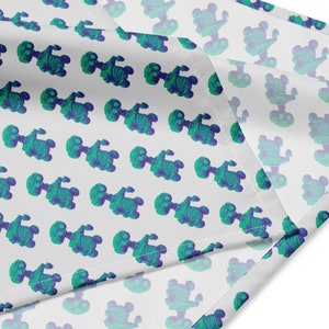 May include: White fabric with a repeating pattern of green and blue skeletons. The fabric is folded over on itself, showing the white underside.