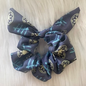 May include: A dark blue scrunchie with a white and blue pattern of the Star Wars Rebel Alliance symbol.