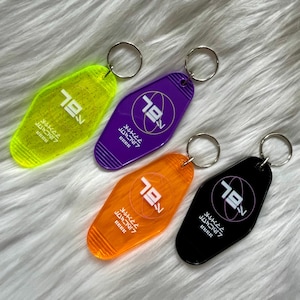 May include: Four retro-style keychains in neon yellow, purple, orange, and black. Each keychain features the number "79" and Japanese text. The keychains have a silver metal ring for attaching keys.