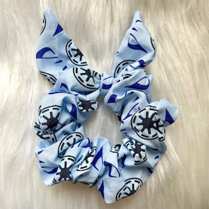 May include: A light blue scrunchie with a repeating pattern of black and blue Imperial symbols from Star Wars.