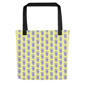 Op de afbeelding: Een gele tote bag met een herhalend patroon van paarse en roze parfumflesjes. De tas heeft zwarte handvatten.