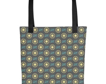 Puede incluir: Bolso tote gris con un patrón repetido de estrellas amarillas y marcas de conteo azules. El bolso tiene asas negras y está diseñado para transportar objetos. El patrón cubre toda la superficie del bolso.