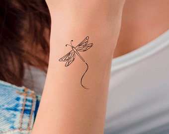 May include: A simple line drawing of a dragonfly tattoo on a person's wrist.
