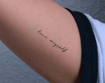 May include: A close-up of a person's arm with a simple black tattoo that reads "love myself" on the upper arm.