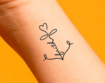 May include: A black and white temporary tattoo of an anchor with a heart at the top. The anchor is drawn in a cursive style.