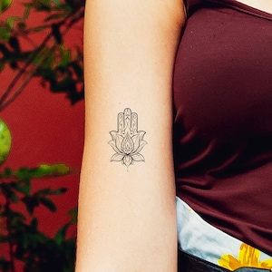 May include: A black and white temporary tattoo of a hamsa hand with a lotus flower design.