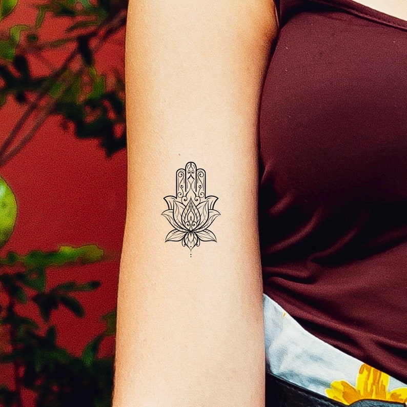 May include: A black and white temporary tattoo of a hamsa hand with a lotus flower design.