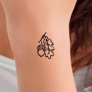 Puede incluir: Un dibujo en blanco y negro de una bellota con una hoja en el brazo de una persona.