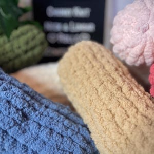 May include: Four different textured fabric swatches in blue, beige, pink and red. The swatches are arranged in a row, with the blue swatch in the foreground.