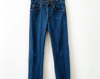 May include: A pair of dark blue denim jeans featuring a high-waisted fit, a button fly closure, and classic five-pocket styling. The jeans have a straight-leg cut with visible copper-toned rivets at the pocket corners and a sturdy waistband.