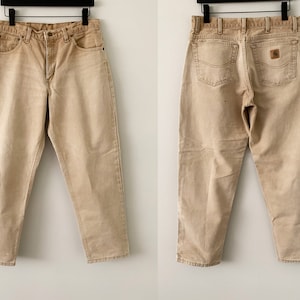 Puede incluir: Un par de pantalones vaqueros de color marr&oacute;n claro con corte recto. Los vaqueros tienen un dise&ntilde;o cl&aacute;sico de cinco bolsillos y un parche de cuero marr&oacute;n en el bolsillo trasero derecho.