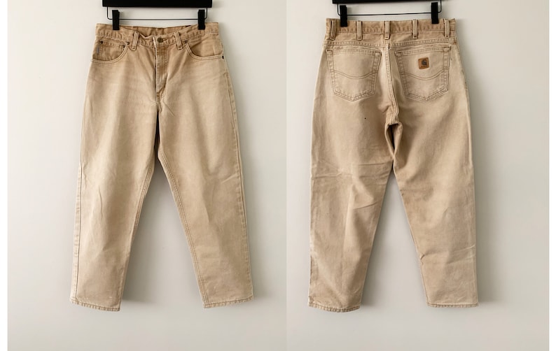 Puede incluir: Un par de pantalones vaqueros de color marr&oacute;n claro con corte recto. Los vaqueros tienen un dise&ntilde;o cl&aacute;sico de cinco bolsillos y un parche de cuero marr&oacute;n en el bolsillo trasero derecho.